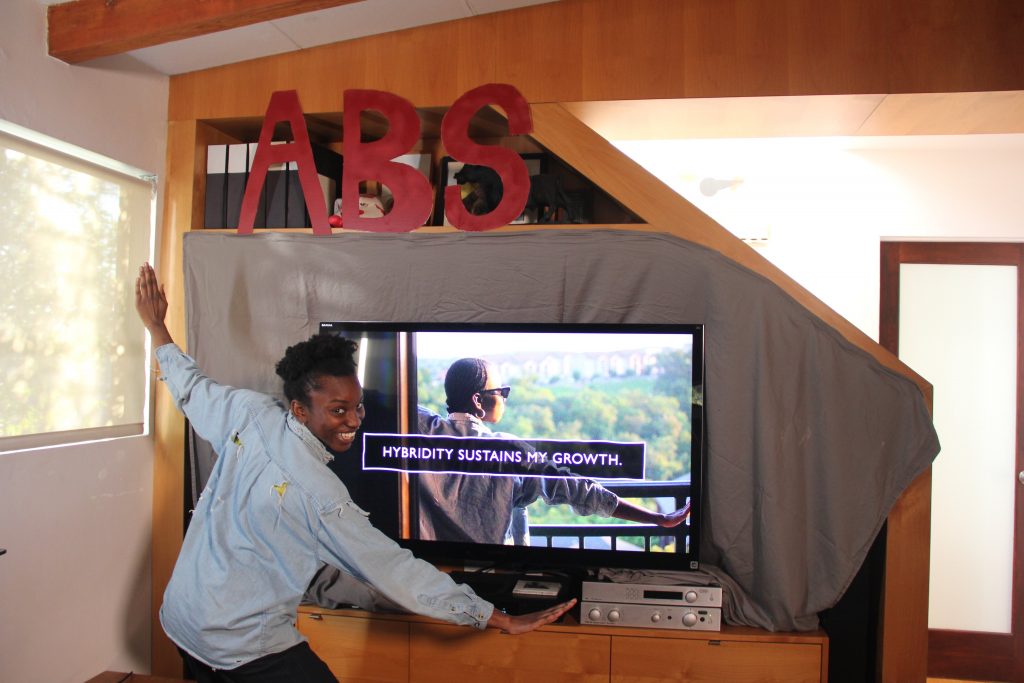 Ashley stands in front of powerpoint slide invoking same posture as on screen, caption reads "Hybridity sustains my growth." 